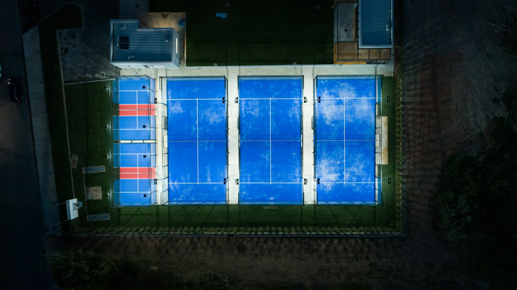 Aerial night view of a row of blue padel courts