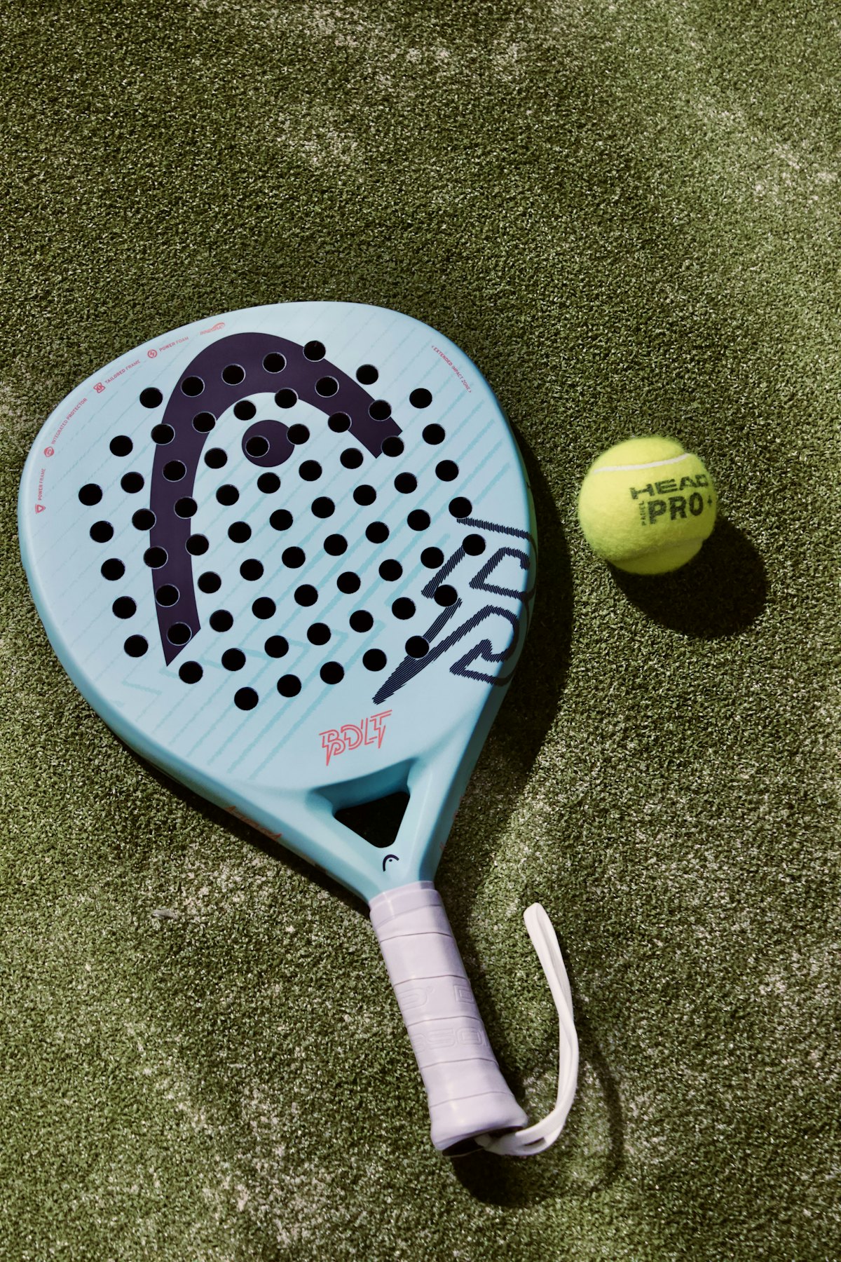 A padel racket and ball on the grass