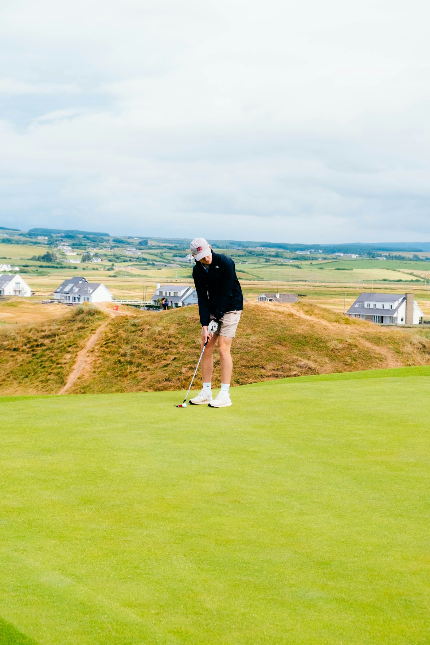 A golfer putting on a links course by the sea