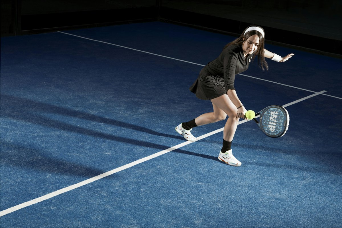 A padel player lunging for the ball