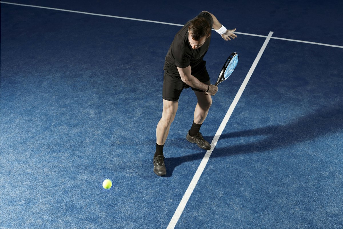 A padel player about to hit a low shot