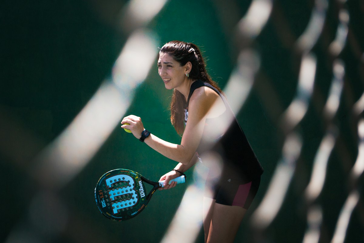 A smiling padel player behind the glass