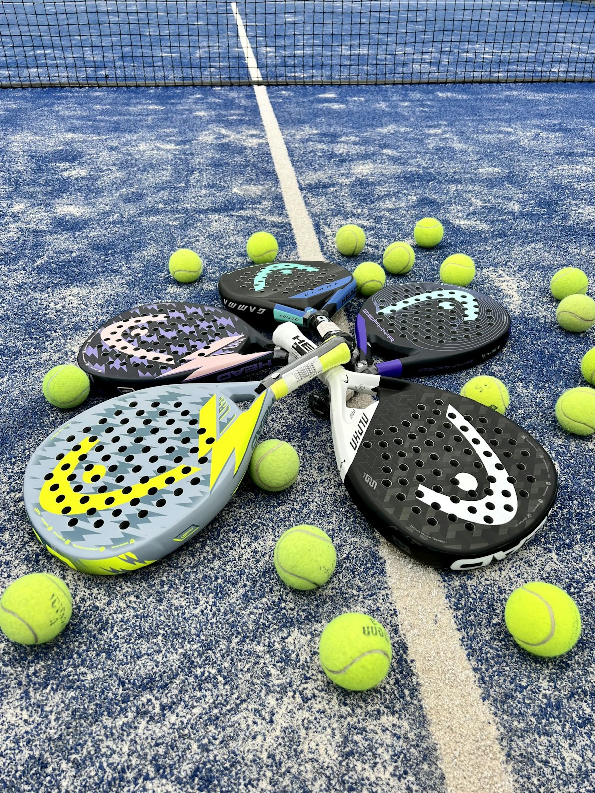 Padel rackets and yellow balls on a blue court
