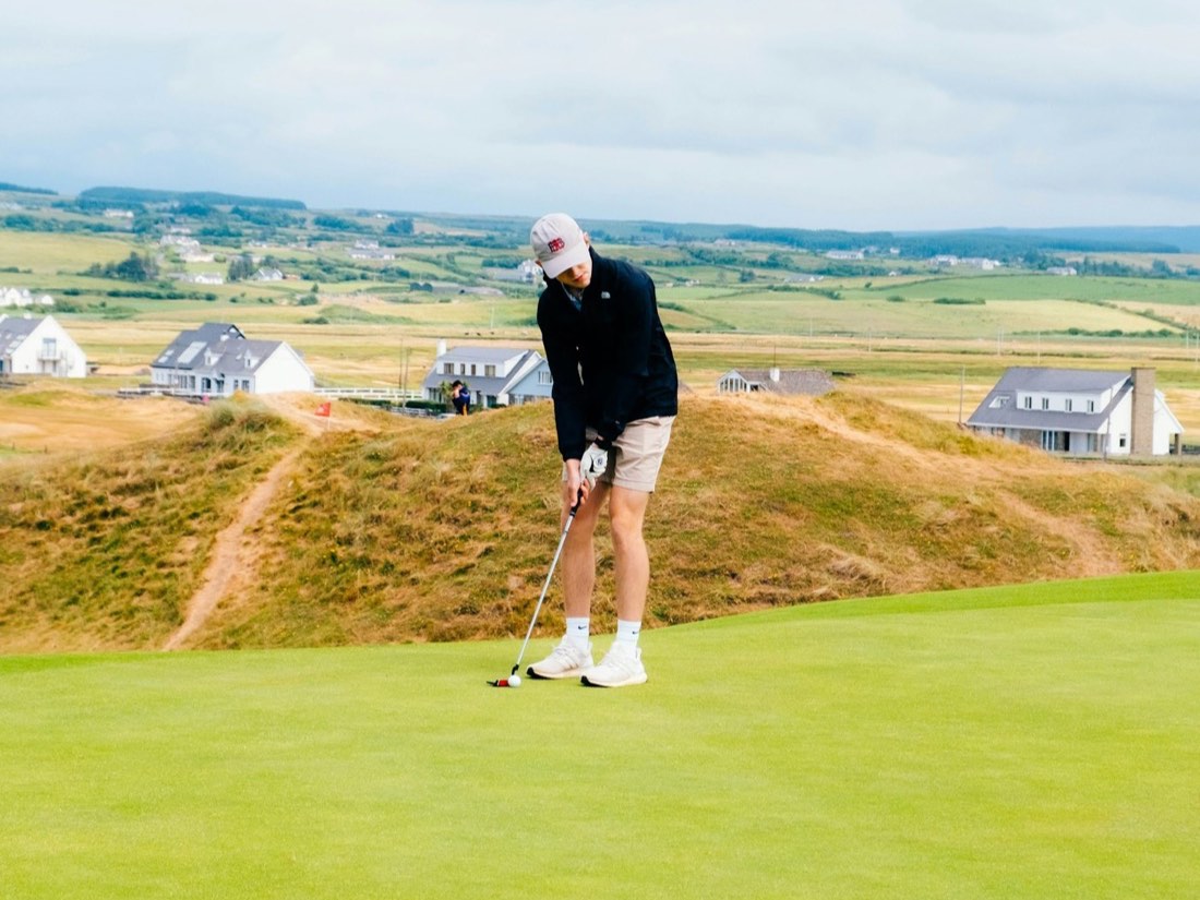 A golfer putting on a links course by the sea
