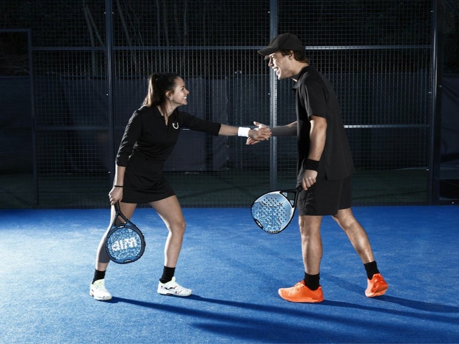 Two padel players shaking hands at the net